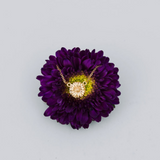 Gold necklace displayed on a purple flower with a light gray background