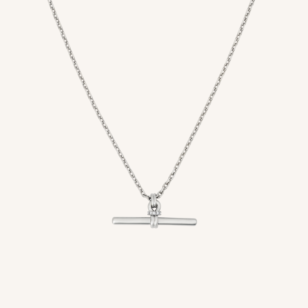 A delicate silver chain necklace with a single round bezel-set clear gemstone pendant, shown against a plain white background.