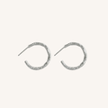 A pair of textured silver crescent hoop earrings with post backs, displayed on a clean off-white background.