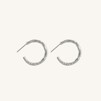 A pair of textured silver crescent hoop earrings with post backs, displayed on a clean off-white background.