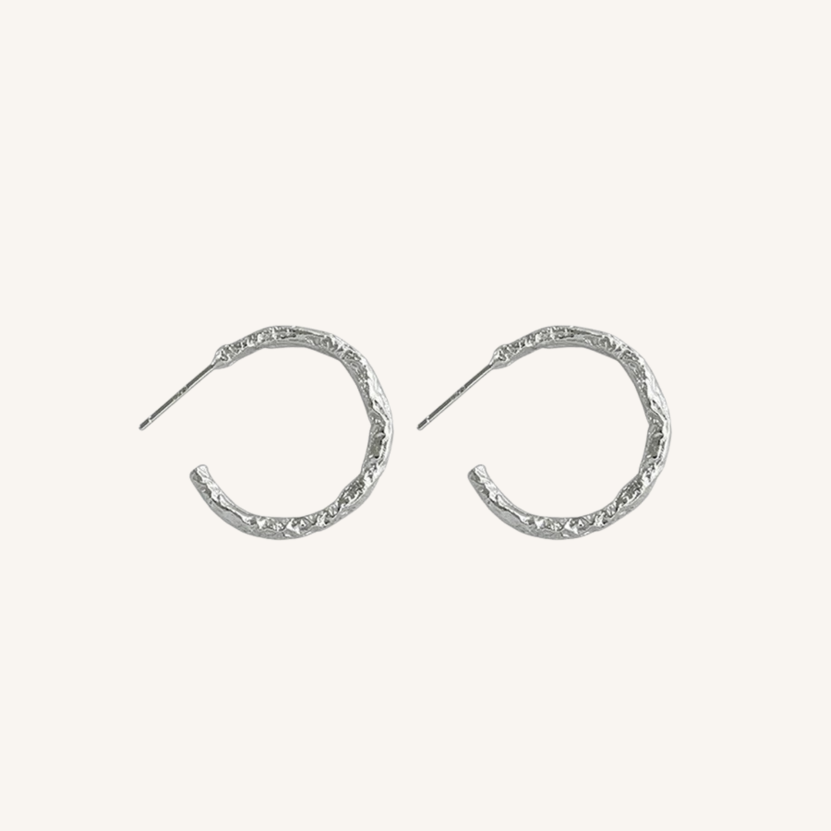 A pair of textured silver crescent hoop earrings with post backs, displayed on a clean off-white background.