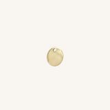 A small round gold disc charm with a hole at the top, centered on a plain off-white background.