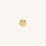 A small round gold disc charm with a hole at the top, centered on a plain off-white background.