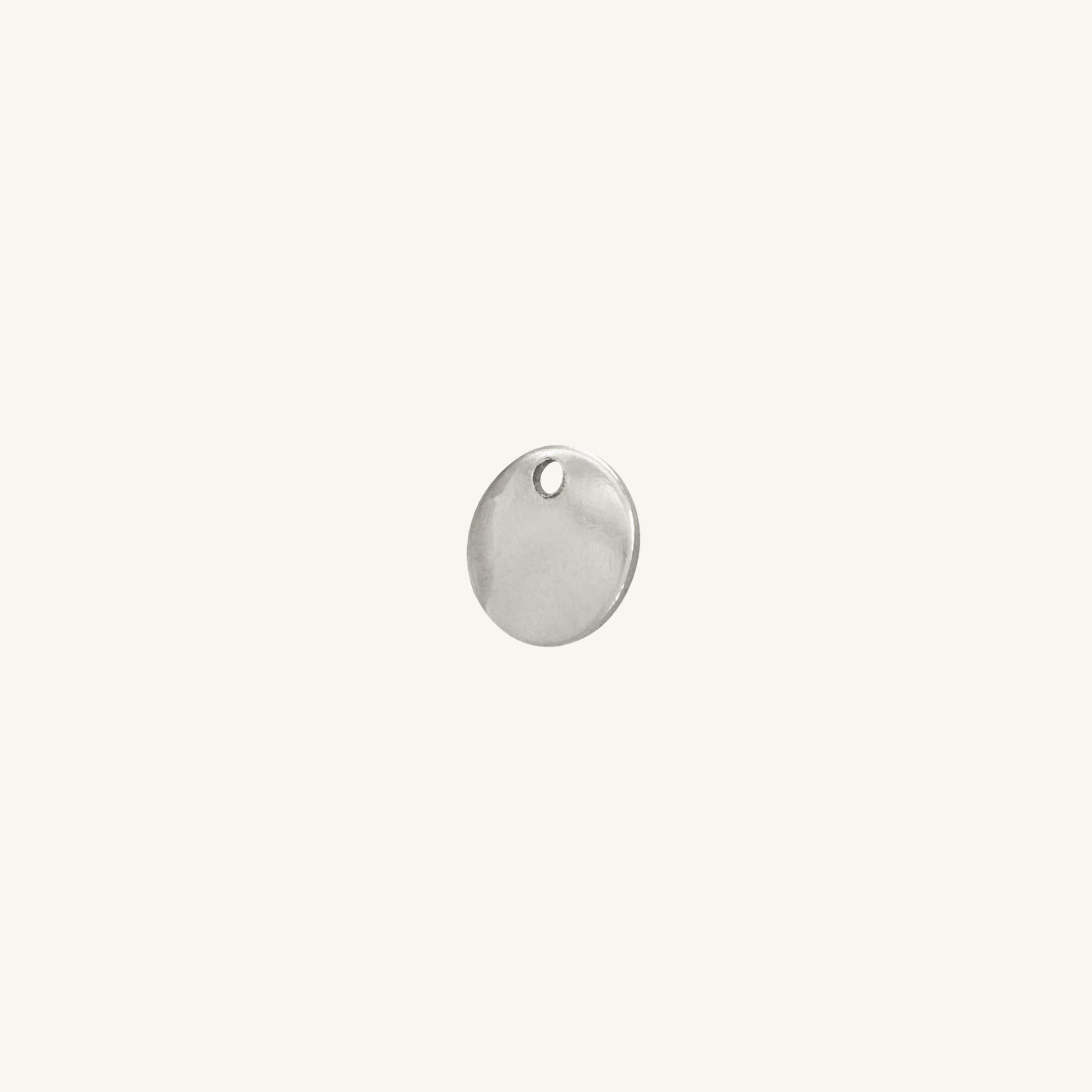 A small round silver disc charm with a hole at the top, centered on a plain off-white background.
