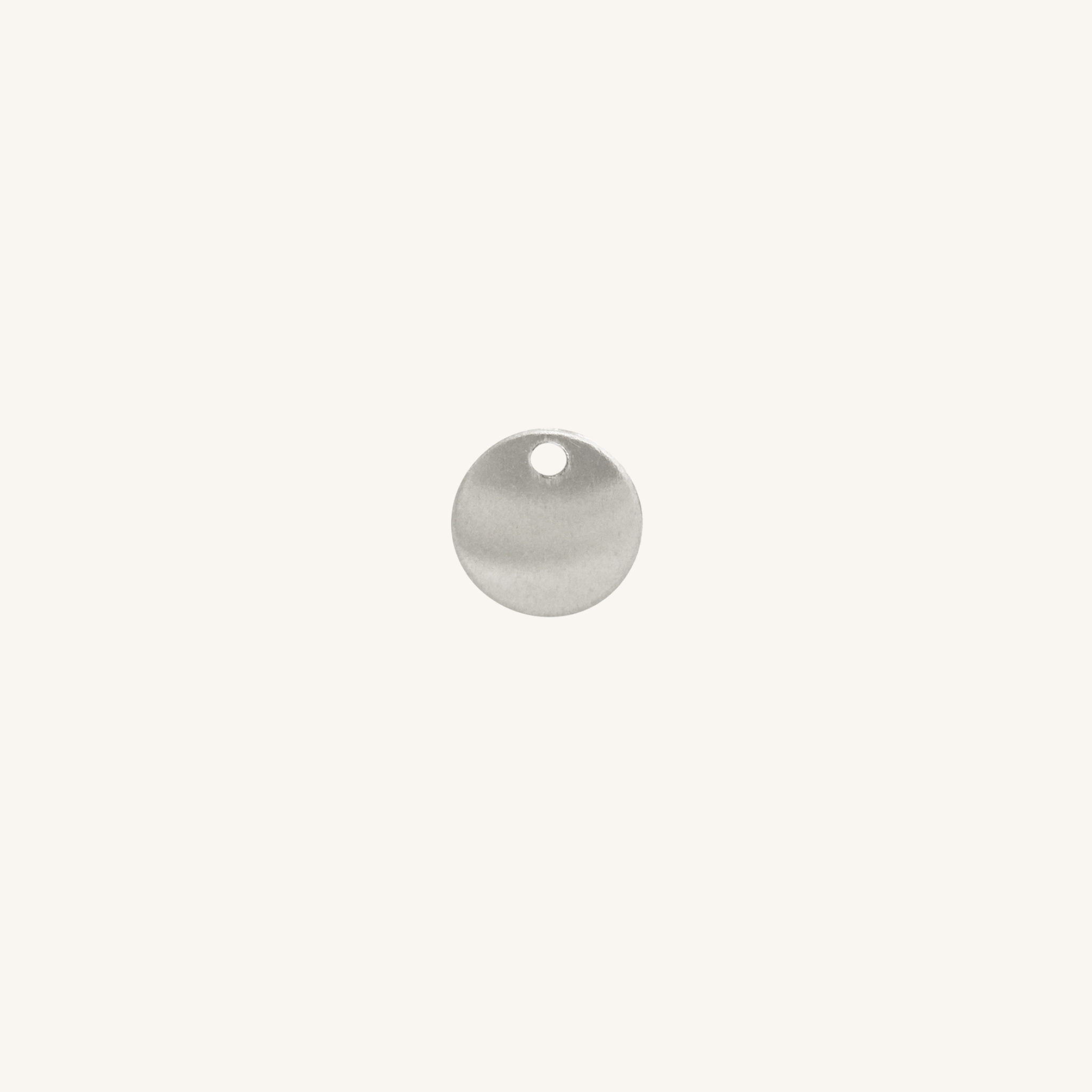 A small round silver disc charm with a hole at the top, centered on a plain off-white background.
