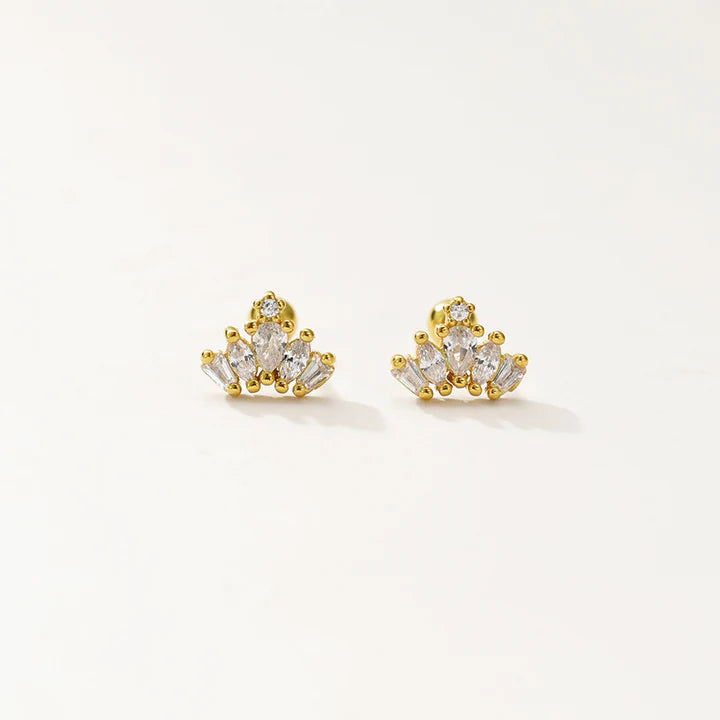 A pair of gold-toned stud earrings with clear gemstones, displayed on a clean off-white background.