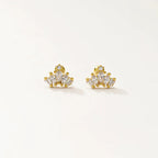A pair of gold-toned stud earrings with clear gemstones, displayed on a clean off-white background.