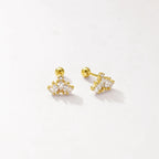 A pair of gold-toned stud earrings with clear gemstones, displayed on a clean off-white background.