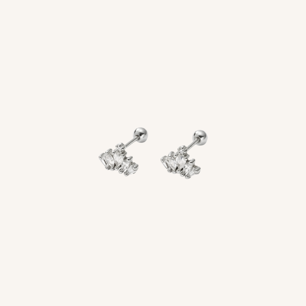A pair of silver-toned labret earrings with small clear gemstone clusters, shown on a plain off-white background.