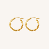 A pair of gold hoop earrings with a twisted rope texture, displayed on a clean, solid off-white background.