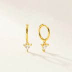 A pair of gold huggie hoop earrings with small triangular clear crystal charms, displayed on a clean off-white background.