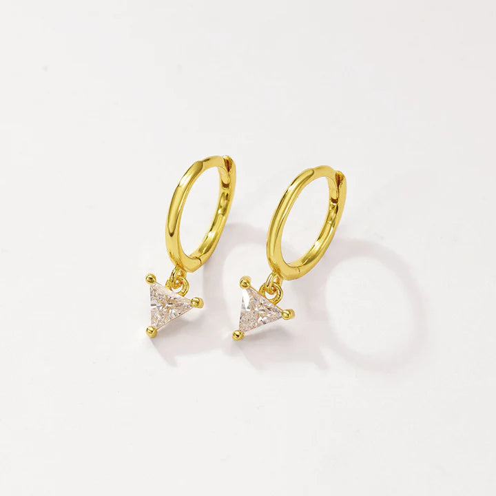 A pair of gold huggie hoop earrings with small triangular clear crystal charms, displayed on a clean off-white background.
