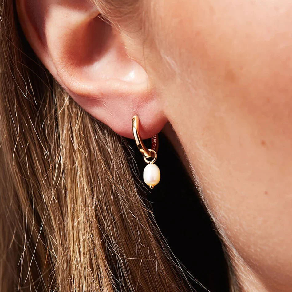 Model Wearing Tilly gold hoop earrings with pearl drops. 