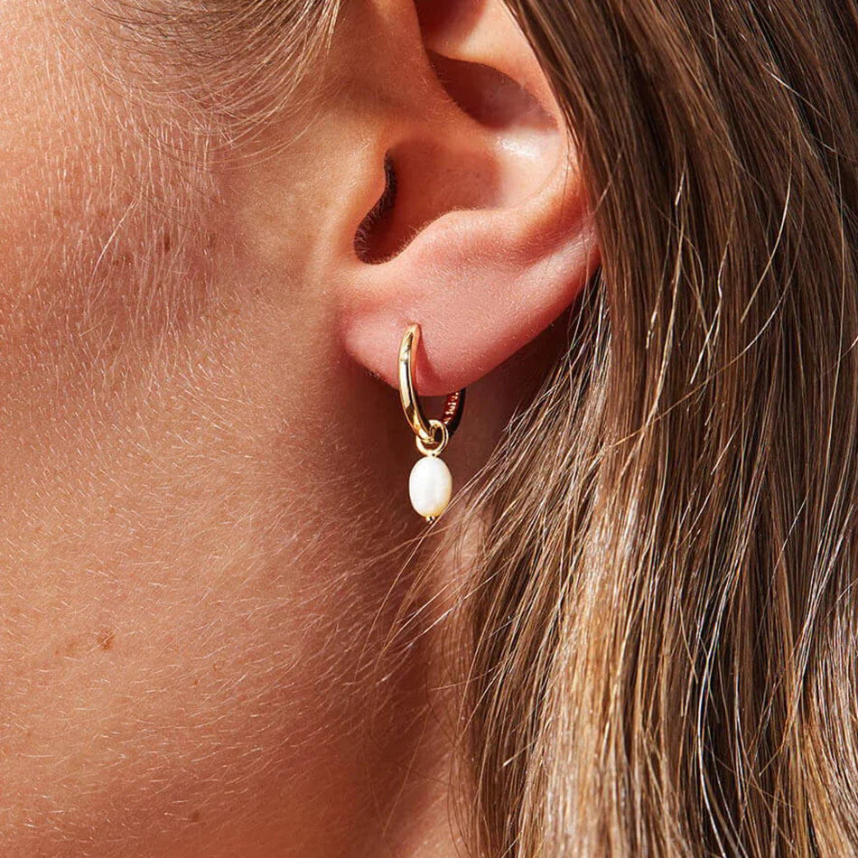 Model Wearing Tilly gold hoop earrings with pearl drops. 