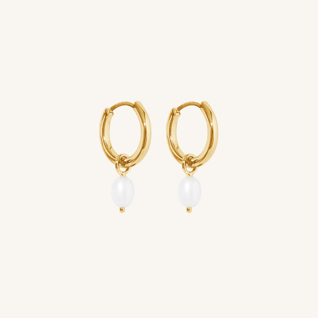 Gold hoop earrings with pearl drops on a white background