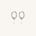 Silver hoop earrings with white pearls on a light beige background