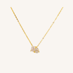 A delicate gold chain necklace with a small pendant featuring two marquise-cut clear gemstones in a gold setting, displayed against a solid off-white background.