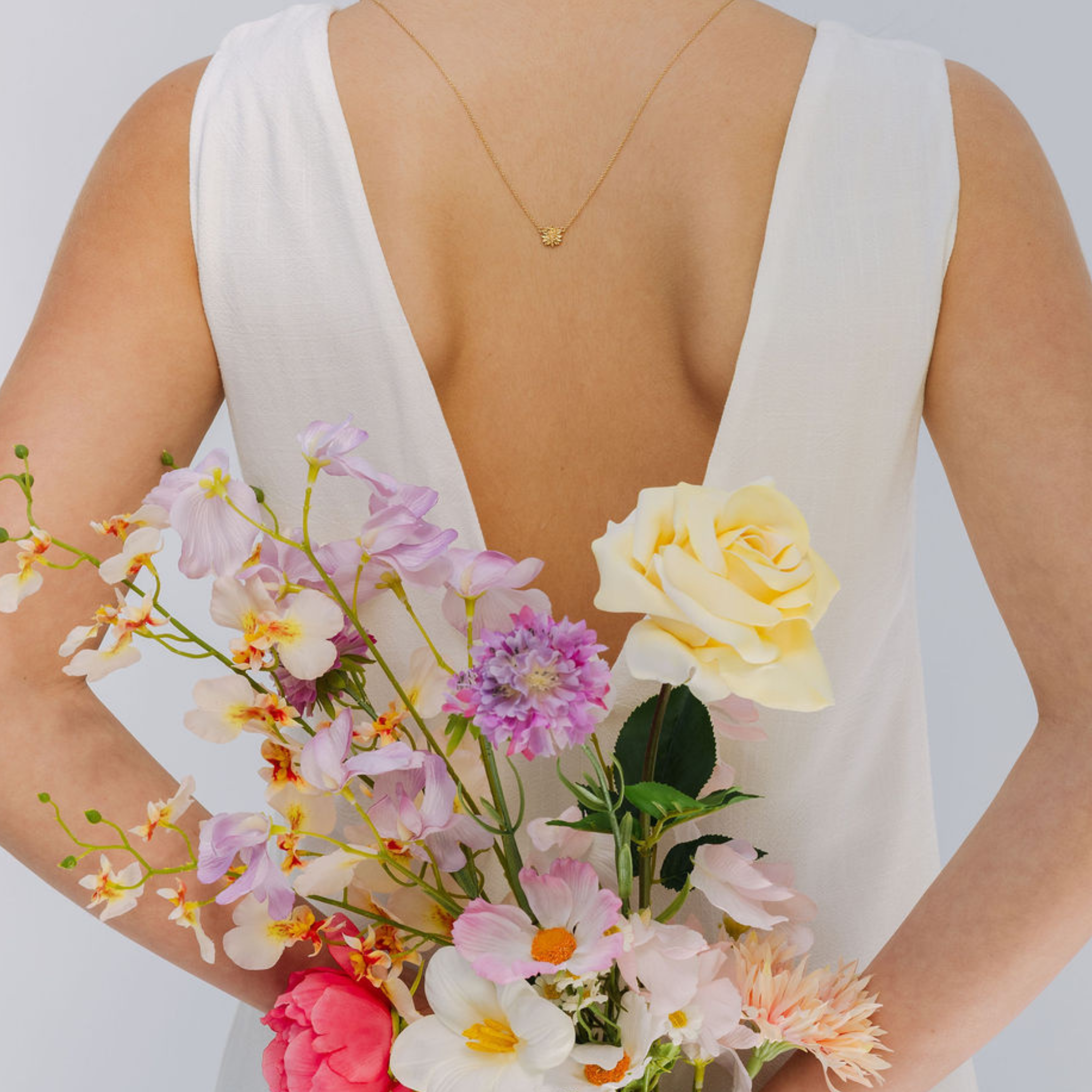 Person wearing a white dress with floral design on the back against a plain background