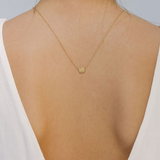 Gold necklace with a pendant on a person wearing a white top