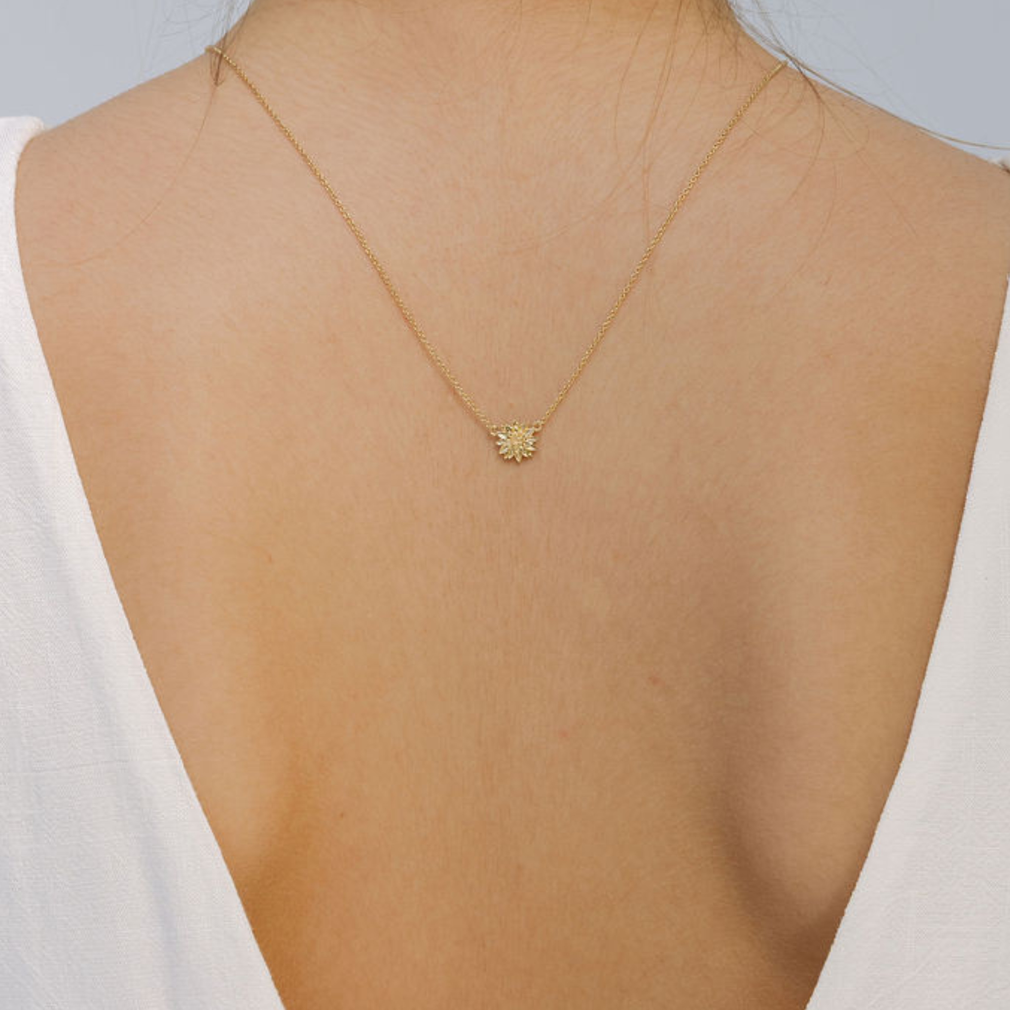 Gold necklace with a pendant on a person wearing a white top
