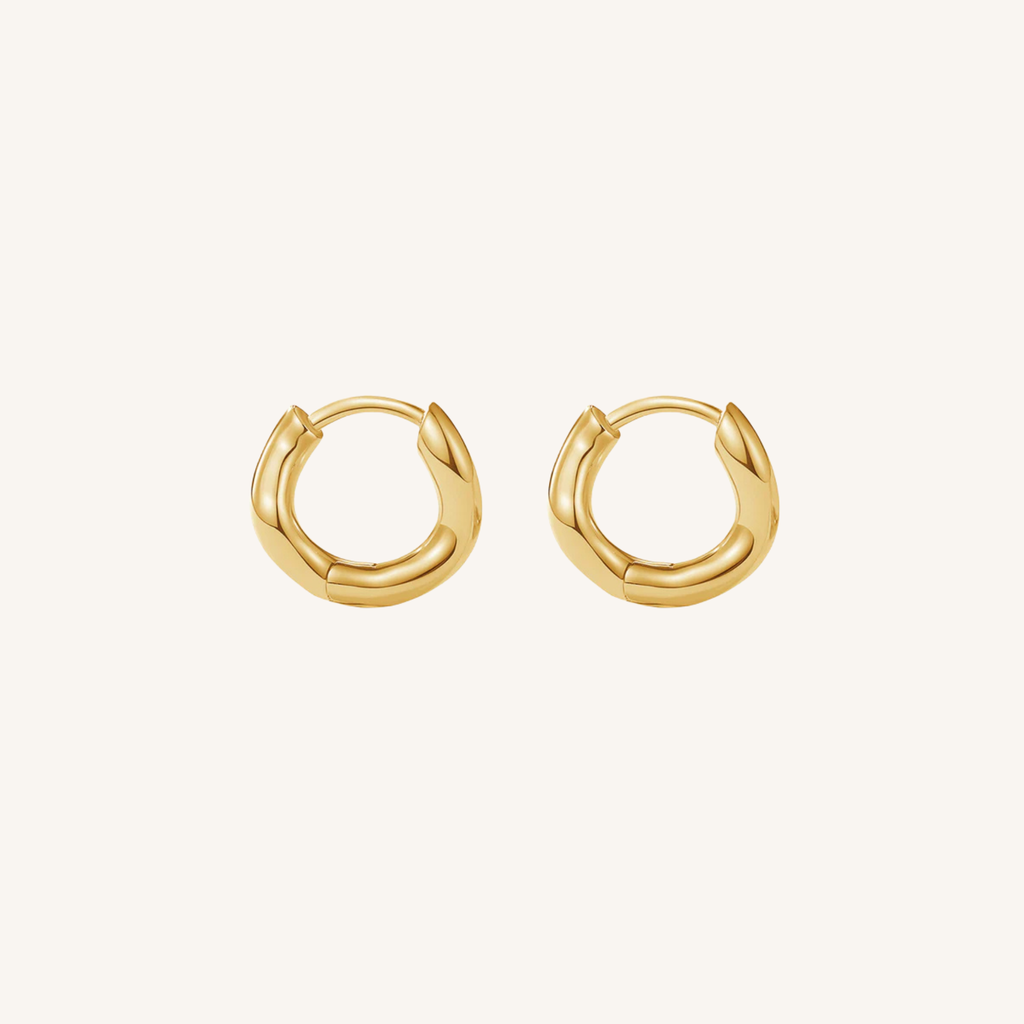 Gold hoop earrings on a light beige background