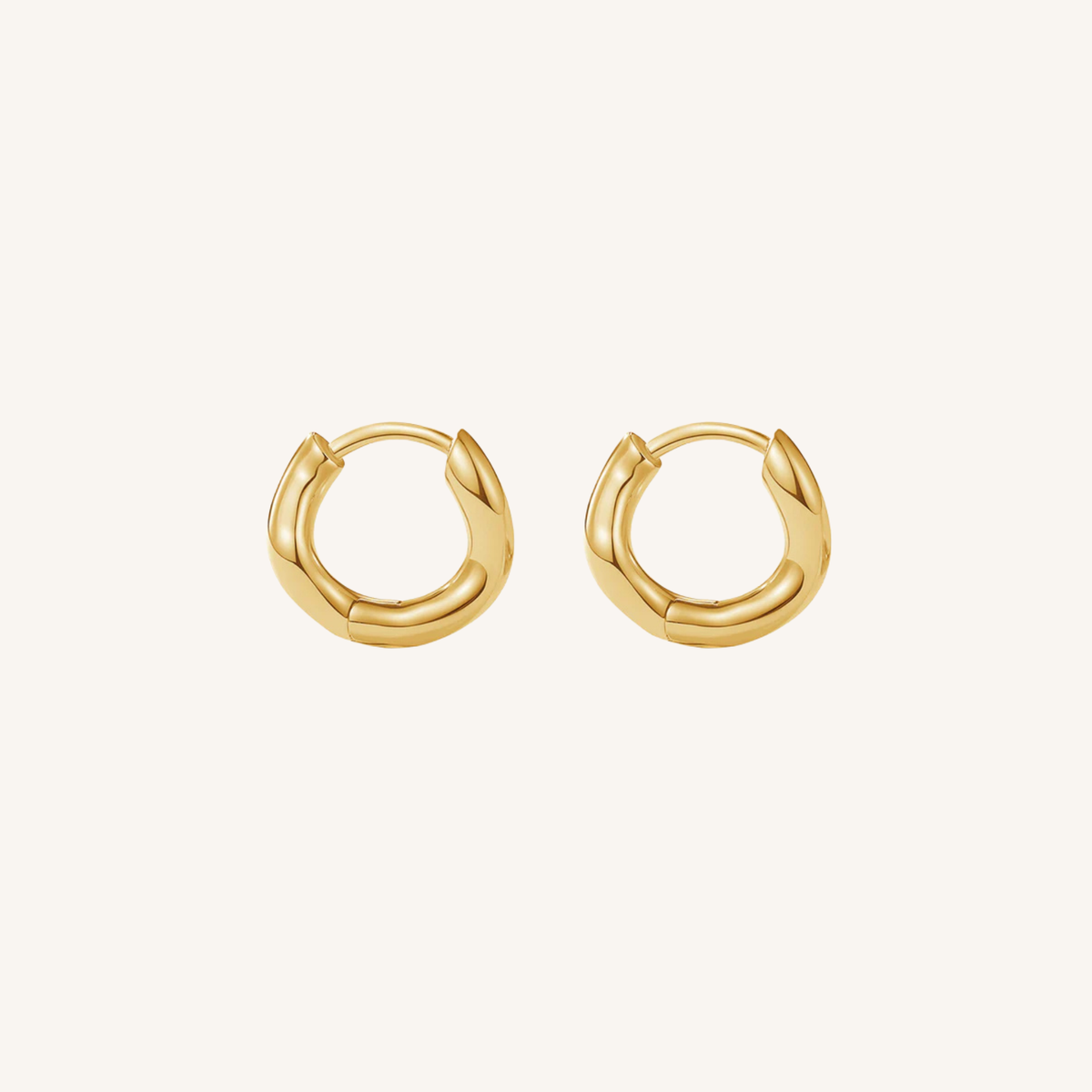 Gold hoop earrings on a light beige background